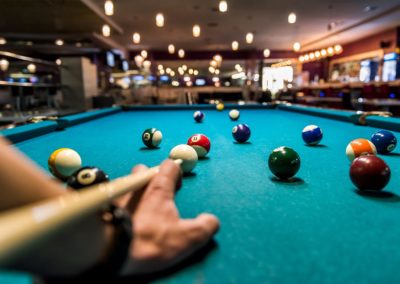 Hand with cue aiming on billiard ball at table