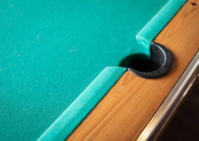 Close up on the side pocket of a pool table with green felt. in a billiards background with space for text on the left