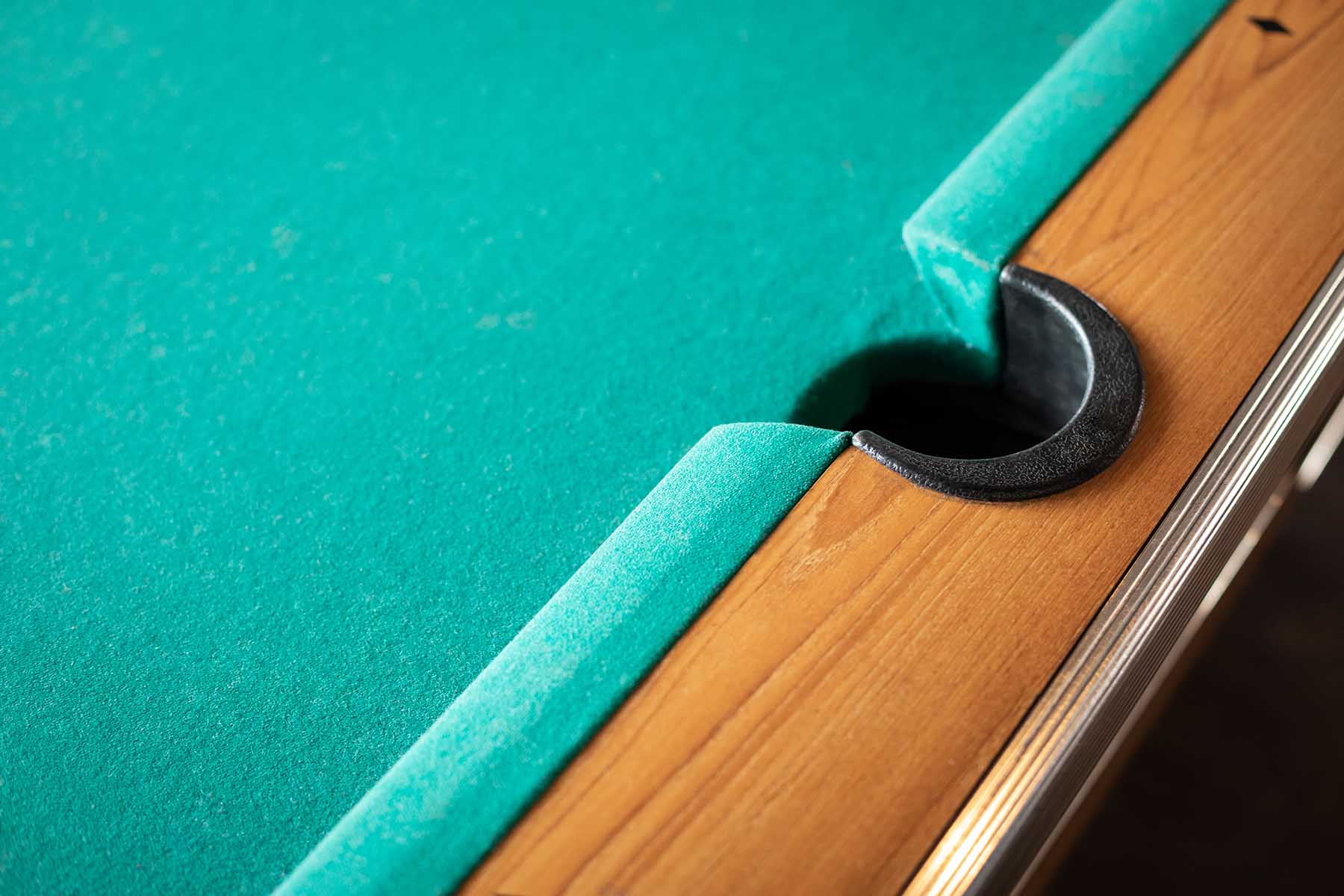 Close up on the side pocket of a pool table with green felt. in a billiards background with space for text on the left